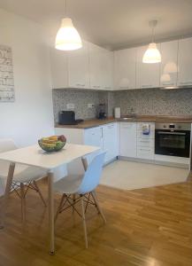 斯科普里Artemis Apartment - nice, family friendly and cozy的厨房配有白色橱柜和桌椅