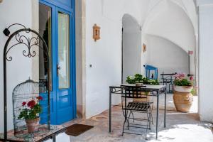 斯蓬加诺Masseria La Macchiola & Corti del Mito的一间设有蓝色门、椅子和植物的房间