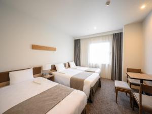 长野长野东急REI饭店的酒店客房设有两张床和一张桌子。