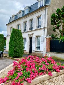 蒂耶里堡Les Remparts de Joussaume Latour的前面有粉红色花的白色房子