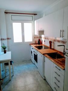 特鲁埃尔Tirwal Suite Judería的厨房配有白色橱柜、水槽和窗户。