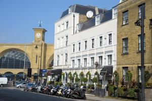 伦敦国王十字客栈酒店的一排摩托车停在有钟楼建筑前面
