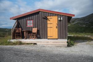 KjøllefjordDavvi Siida - Reindeer Design Lodge的一个带桌子和两把椅子的小棚屋
