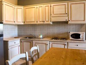 圣温琴佐Apartment Superior-4 by Interhome的厨房配有木制橱柜、桌子和微波炉