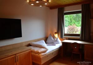 RettenschössGlückchalet的客房设有一张带书桌的床铺和一台电视。