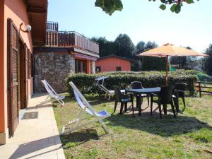 勒威诺Holiday Home Residenza Agrifoglio-11 by Interhome的庭院配有桌椅和遮阳伞。