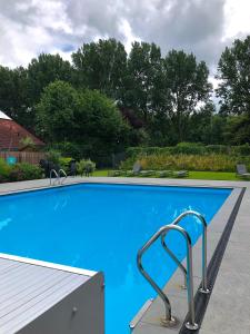 诺德施华伍德莫勒格鲁特酒店的一个带金属扶手的蓝色游泳池