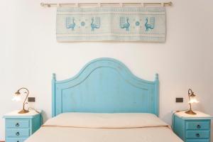 圣彼得罗镇Piccola casa Marina的一张带蓝色床头板和2个床头柜的床