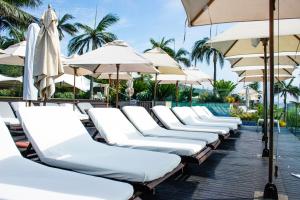 德班海滨放松假日公寓的一把带遮阳伞和游泳池的白色躺椅