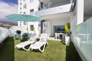 阿德耶Oceanfront Rental的阳台配有椅子、雨伞和桌子。
