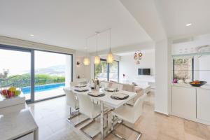 卡斯Luxus Villa Skyla mit 5 Schlafzimmern & Meer-Blick的白色的厨房和带桌椅的用餐室