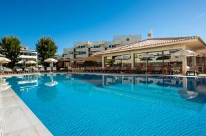 阿尔布费拉海神旅馆公寓的一座带桌子和遮阳伞的大型游泳池