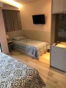 嘎林海斯港Studio Experience Marulhos Resort的酒店客房设有两张床和一台平面电视。