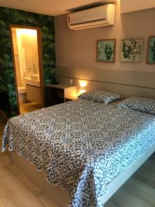 嘎林海斯港Studio Experience Marulhos Resort的一间卧室配有一张带蓝色和白色棉被的床
