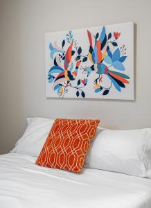 卡尔加里Contemporary 1br Home Full Kitchen Smarttv的一张带橙色枕头的床和墙上的绘画