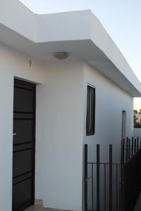 奥夫雷贡城Hotel Bugambilias的一间白色的房子,设有黑色的门和栅栏