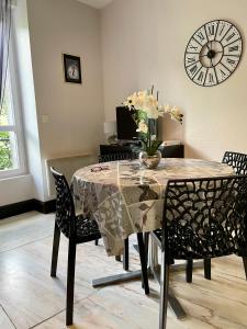 勒蒙多尔Residence Soleil des Thermes 2的餐桌、椅子和墙上的时钟