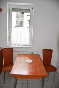 伦蒂Pilikán Apartments Lenti的一张带两把椅子的木桌和窗户