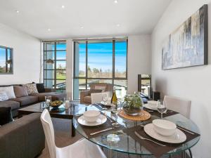陶波24 Marina View Retreat - Taupo Holiday Apartment的客厅配有玻璃桌和椅子