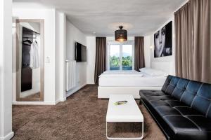 沃尔特湖畔韦尔登Hotel 24 Checkin Velden的客厅配有黑色沙发和床。
