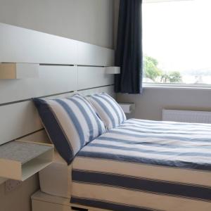 GlandoreCrow's Nest Glandore - 1 - Self Catering的一间卧室配有一张带蓝色和白色床单的床和窗户。