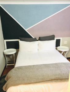 纽卡斯尔VnA Guesthouse的一间卧室配有一张大床和两张凳子