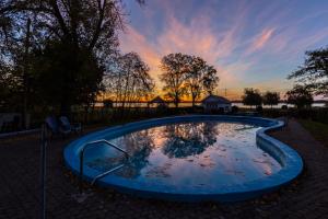 三河城圣洛朗乡间酒店的庭院中的一个小游泳池,背景是日落