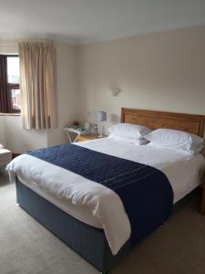 纽马基特拜耶尔雷别墅酒店的一间卧室配有一张带蓝白色床单的大床