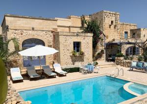 沙拉L'Gharix Temple Retreat的一座带椅子和遮阳伞的游泳池位于大楼旁