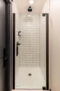 伊萨卡The Dorm Hotel的带淋浴和白色瓷砖淋浴的浴室