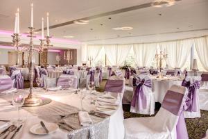 拉恩巴里加里城堡酒店的宴会厅配有白色桌子和紫色椅子