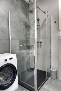 波兹南Essence Apartments Topaz的一间带玻璃淋浴间的浴室内的洗衣机