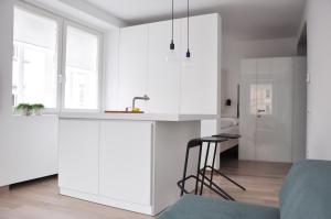 卢布尔雅那艾美一室公寓酒店的厨房配有白色橱柜、水槽和凳子
