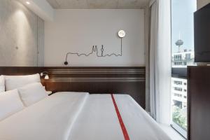 科隆Ruby Ella Hotel Cologne的卧室设有一张白色大床和一扇窗户。