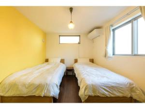 东京rakuna Inn Dou-sasazuka - Vacation STAY 47231v的配有两张床的客房,设有黄色的墙壁和窗户