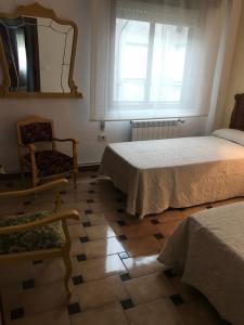 桑亨霍Playa Silgar en Galicia的一间卧室配有两张床、镜子和椅子