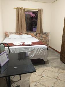 韦尔卡鲍Chalés Vila Bela Vale do Capão的一间卧室配有一张带桌子和窗户的床