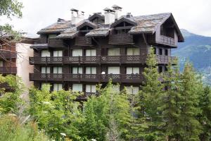 谷雪维尔Courchevel 1550 – VERITABLE SKI AUX PIEDS – APPARTEMENT LES TOVETS T2 – 47m2 – 4P的一座大型的木质建筑,前面有树木