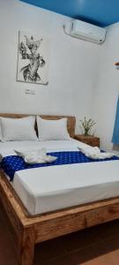 沙努尔龟岛民宿的一间卧室配有一张带蓝色和白色床单的木床。
