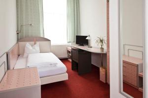 格赖夫斯瓦尔德阿德勒酒店的一间卧室配有一张床和一张带电脑的书桌