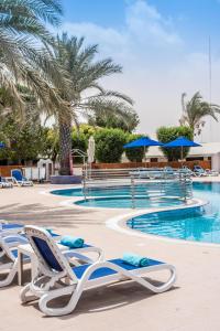 拉斯阿尔卡麦BM Beach Resort的毗邻度假酒店的带躺椅和椅子的游泳池