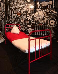 利耶帕亚Karosta Prison的一张红色的床,位于一间黑白墙的房间里