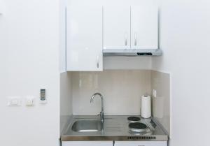 杜布罗夫尼克艾姆一室公寓的厨房配有白色橱柜和水槽
