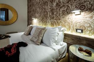 乌迪内梅卡托维奇奥豪华套房酒店的卧室配有带白色枕头和墙壁的床。