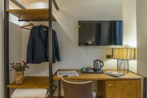 罗马纳沃纳精品酒店的一间房间,配有书桌和挂在架子上的外套