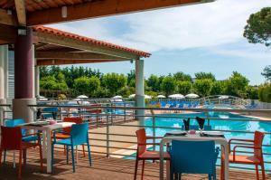 曼德琉-拉纳普勒Goélia Mandelieu Riviera Resort的游泳池旁带桌椅的天井