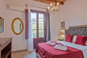 巴塞罗那阿尔卡姆图书酒店的一间卧室配有一张大床,配有红色床单和镜子