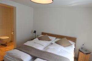 GuttannenHotel Bären Guttannen的一间卧室配有带白色床单和枕头的床。