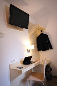 里沃萨尔特Kyriad Direct Perpignan - Aeroport的一张带笔记本电脑的桌子和一台墙上的电视