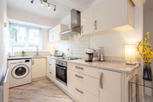 MoortownCosy 2 Bed Apartment - Close to Leeds Centre的厨房配有白色橱柜、洗衣机和烘干机